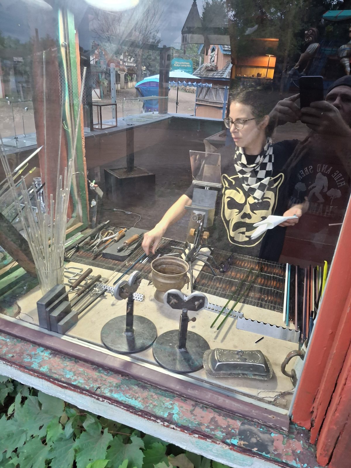 Friendly Fire glass artist working the torch, festival grounds behind